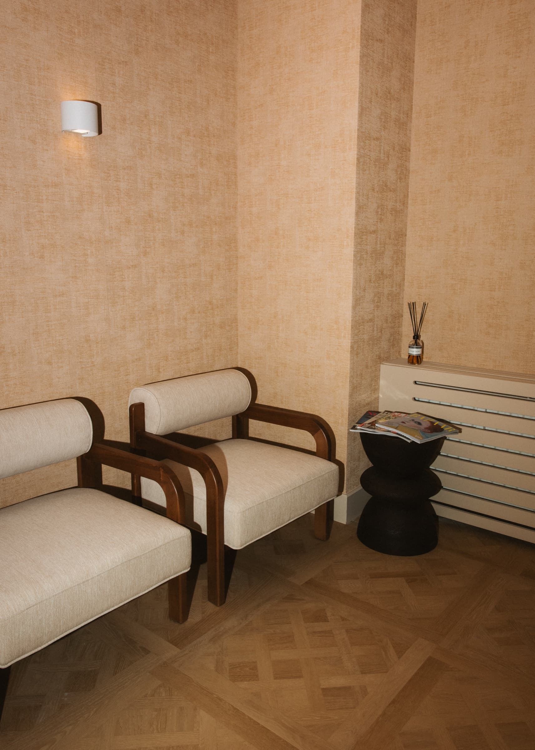 Wachtruimte met twee crèmekleurige fauteuils en een klein bijzettafeltje